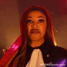 a woman with red hair and blue eye shadow is wearing a superhero costume and making a funny face ..