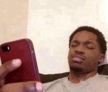 a man is sitting on a couch looking at his cell phone and making a funny face .