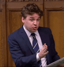 a man in a suit and tie holds a piece of paper in his hand