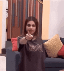 a woman is pointing at the camera in a living room .