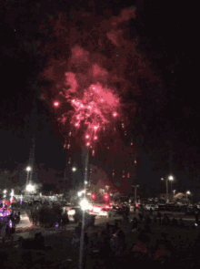 a fireworks display is being watched by people in a parking lot