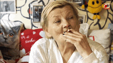 an elderly woman smoking a cigarette in front of a pillow that says " da liebe "