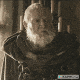 a man with a beard is sitting in a chair and looking at a piece of paper that says kapwing