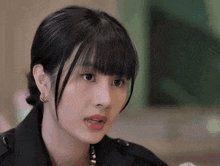 a close up of a woman 's face with a black jacket and earrings .