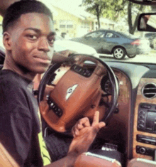 a man is sitting in a bentley car and giving the middle finger