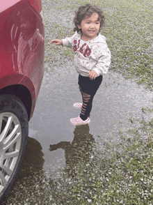 a little girl in a gap sweatshirt stands in a puddle