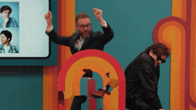 a man in a suit stands in front of a rainbow shaped sign