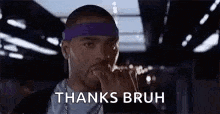 a man wearing headphones and a purple headband is holding his hand to his mouth .