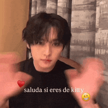 a young man is making a heart with his hands and says " saluda si eres de kitty " on the bottom