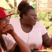 a woman in a white shirt is sitting next to a man in a red hat