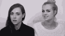 two women are sitting next to each other in a black and white photo and looking at the camera .