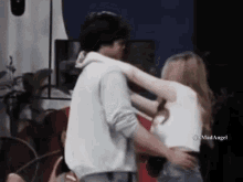 a man and a woman are hugging each other .
