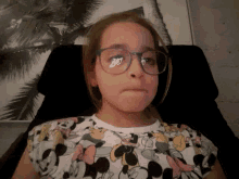 a woman wearing glasses and a minnie mouse shirt is laying upside down