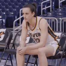 a female basketball player is sitting on a chair in an empty basketball court .