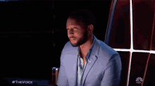 a man in a blue suit is sitting in front of a nbc sign