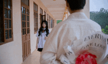 a girl in a white shirt that says " everyday love love " stands next to a boy