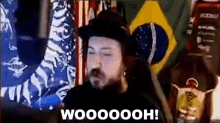 a man in a hat is standing in front of a brazilian flag and a american flag .
