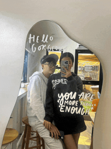 a couple taking a picture in front of a mirror that says hello gorgeous on it