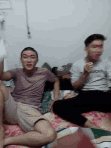 two men are sitting on a bed with red paint on their faces .