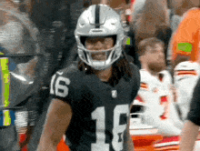 a football player wearing a helmet and number 16 on his jersey is standing in a crowd .