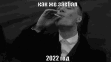 a black and white photo of a man smoking a cigarette with the year 2022 written below him