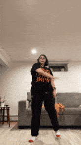 a woman is dancing in a living room wearing a black shirt that says " evil "