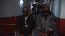 two men are standing in a hallway and one is holding a bottle that says ' coca cola ' on it
