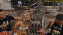 a man wearing another shot is talking to a woman sitting on a bench