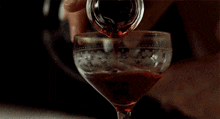 a person pouring red liquid into a glass with a floral design