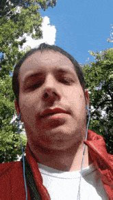 a man wearing headphones and a red jacket is looking at the camera