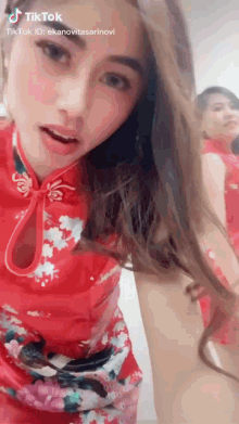a woman in a red dress is standing in front of a mirror and looking at herself .