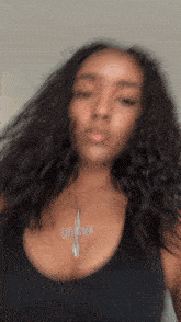 a woman wearing a black tank top with a cross necklace