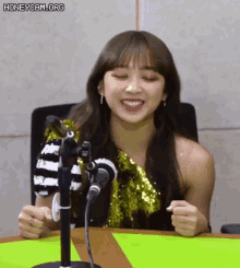 a woman is sitting at a table with a microphone and smiling .