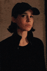 a woman wearing a hat and a black jacket looks at the camera