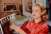 a woman in a red shirt reads a magazine called bazaar