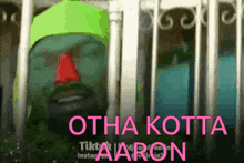a man in a green hat is behind bars with the words otha kotta aaron in pink letters