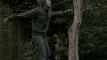 a man laying on his back with his arms outstretched next to a tree