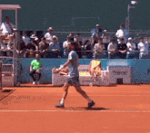 a man playing tennis on a court with a polaroid sign behind him