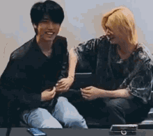 a couple of men are sitting on a couch laughing and playing with each other .
