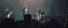 a group of men are playing guitars on stage in front of a crowd .
