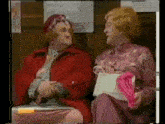 two women are sitting next to each other on a bench and talking .