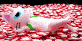 a white cat with blue eyes is laying on a pile of red and white poker chips