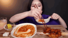 a woman is eating a bowl of food with chopsticks and a spoon