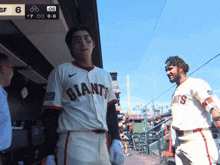 two giants baseball players are talking to each other in the dugout