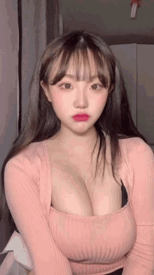 the girl is wearing a pink sweater and a black bra and has a very large chest .