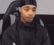 a person is sitting in a chair with their arms crossed and making a funny face .