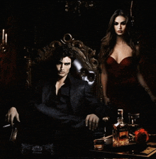 a man sitting in a chair next to a woman in a red dress