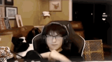 a man wearing headphones and glasses is sitting in a gaming chair .