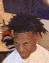 a man with dreadlocks is sitting in a chair and looking at the camera