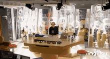 a man is sitting at a table with a laptop and a microphone in front of a sign that says immagine italia